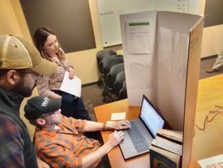 Three people looking at a computer