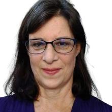 Woman with long brown hair and glasses smiling.