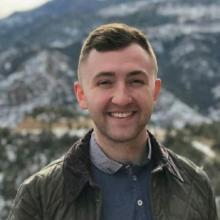 Man smiling with mountains behind him
